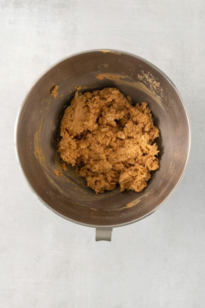 Overhead view of combined ingredients for peanut butter balls  in a silver mixing bowl.