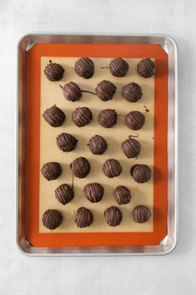 Overhead view of chocolate dipped peanut butter rice krispie treat balls on a parchment lined baking sheet.