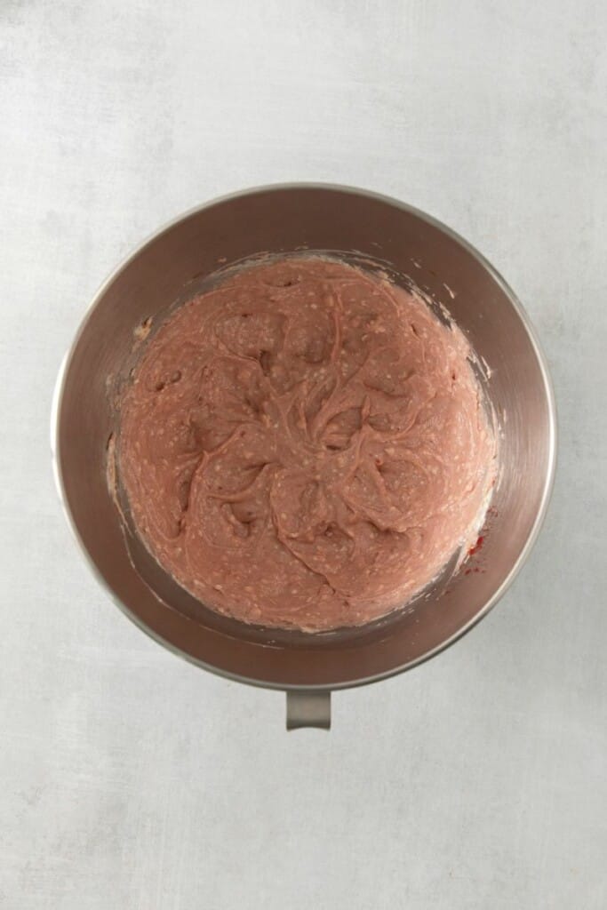 Butter, cream cheese, jam and vanilla extract combined in a silver mixing bowl.