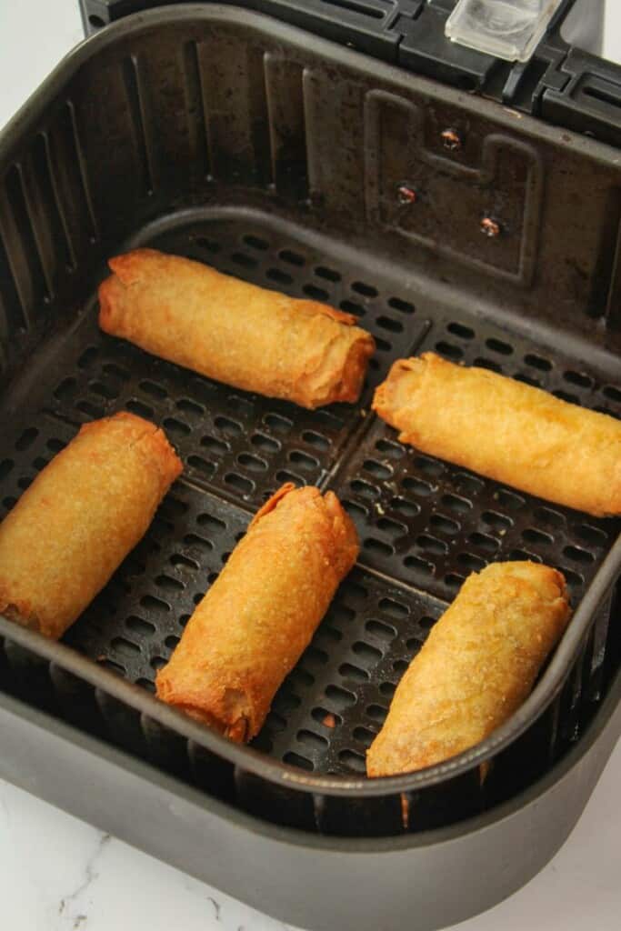 Reheated egg rolls in an air fryer basket