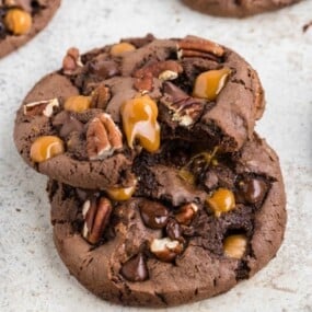 Two prepared turtle cookies stacked on one another, the top cookie has a bite taken out.