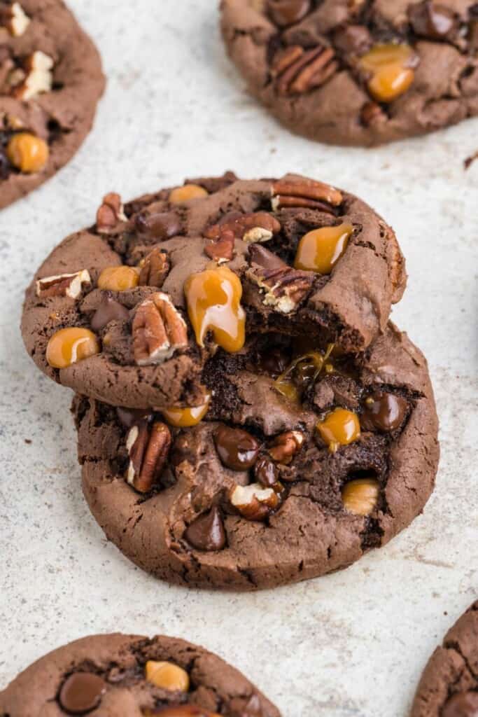 Two prepared turtle cookies stacked on one another, the top cookie has a bite taken out.