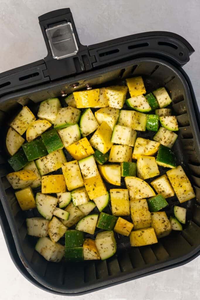 Raw zucchini and squash in the air fryer basket.