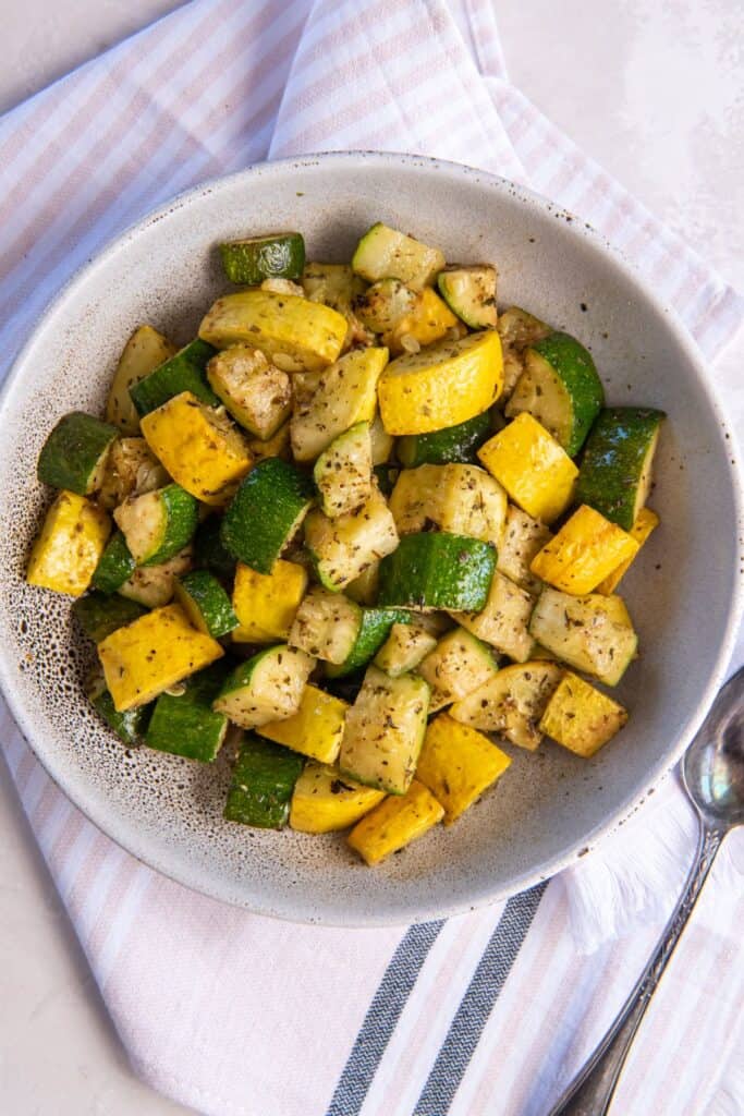 Overhead shot of air fryer squash and zucchini in a white bowl.