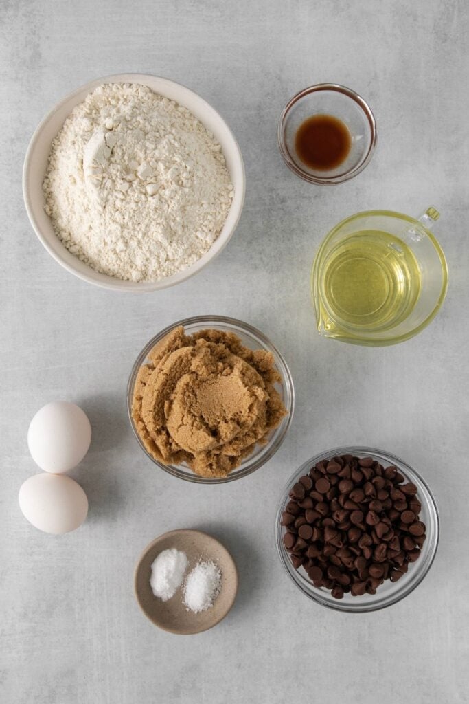 Ingredients needed to make chocolate chip cookies no butter: vegetable oil, brown sugar, eggs, vanilla extract, flour, baking soda, salt, and chocolate chips.