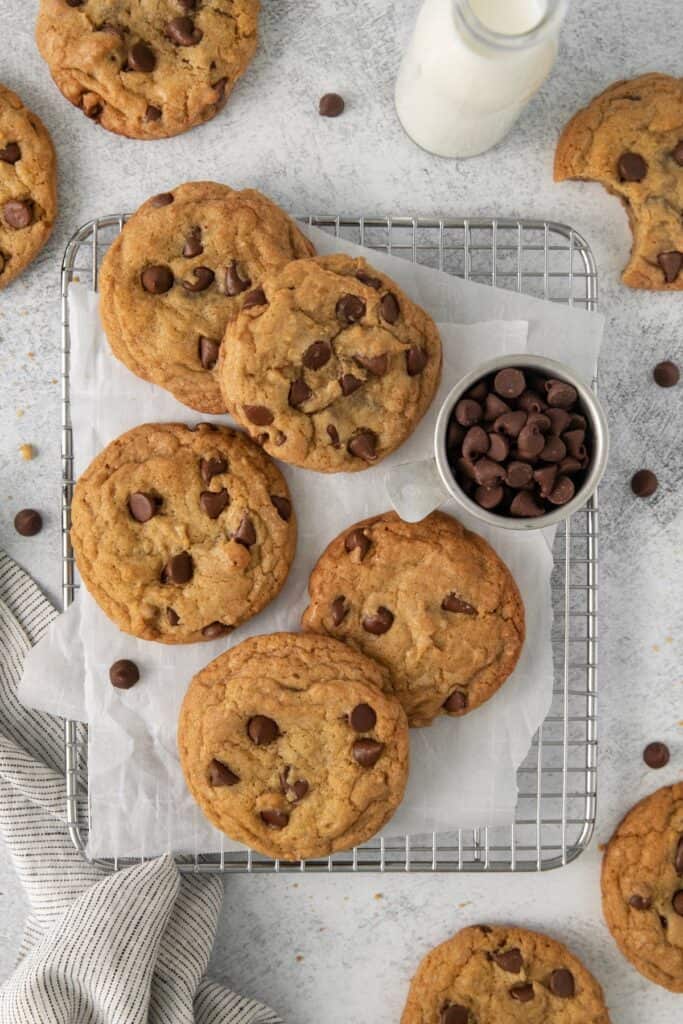 Chocolate chip cookies with no butter on a wire rack with a little bowl of chocolate chips next to it.