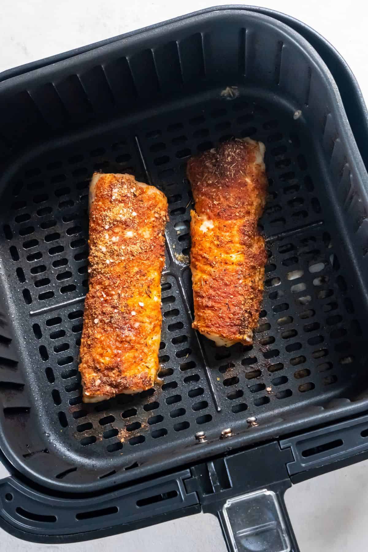 Cooked frozen cod in an air fryer basket.