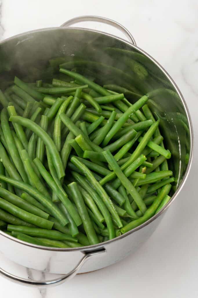 Steamed green beans in a large stainless steel pot.