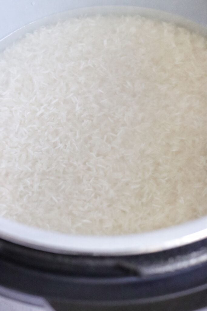 Rice in the Ninja Foodi fully submerged in water before pressure cooking.