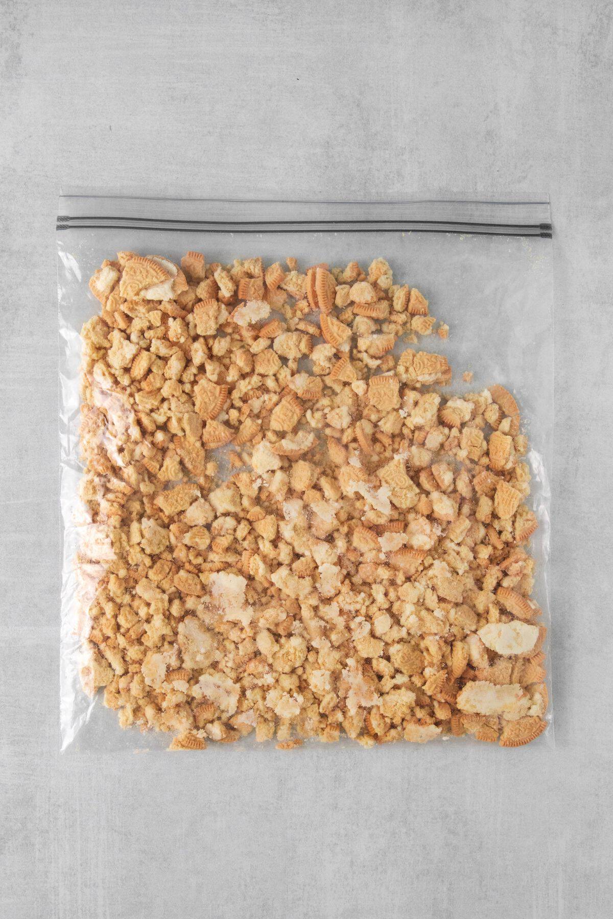 Golden Oreos in a Ziploc bagged being pounded into pieces.