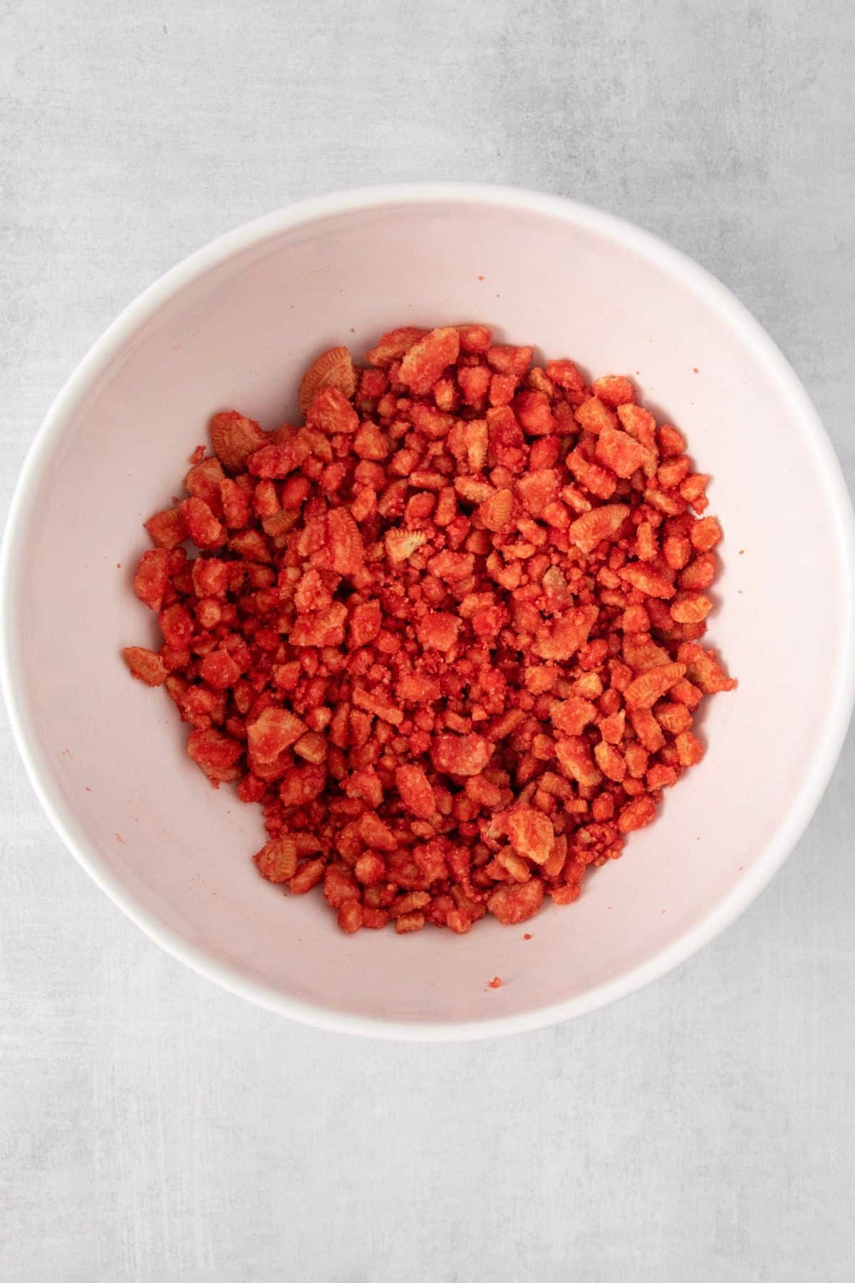 The strawberry crunch mixed with the strawberry gelatin in a bowl.