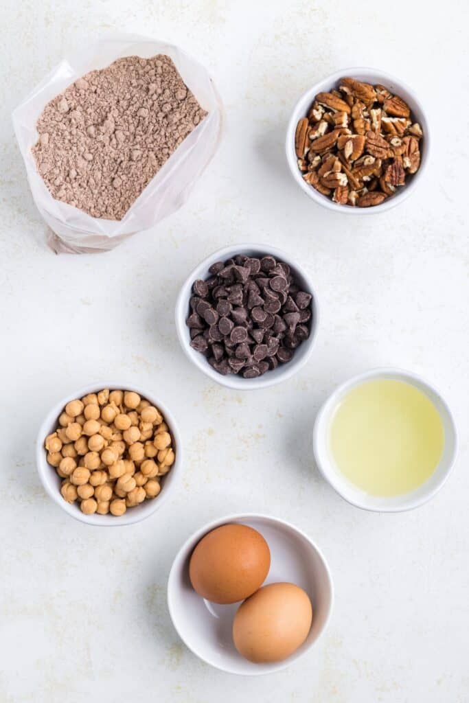 Ingredients needed to make turtle cookies: chocolate cake mix, eggs, vegetable oil, caramel bits, pecans, and chocolate chips.