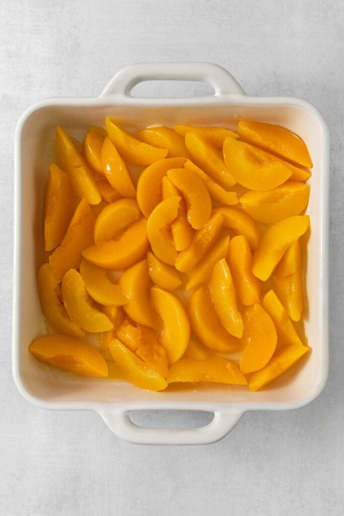 Canned peaches in a 9x9 baking dish.