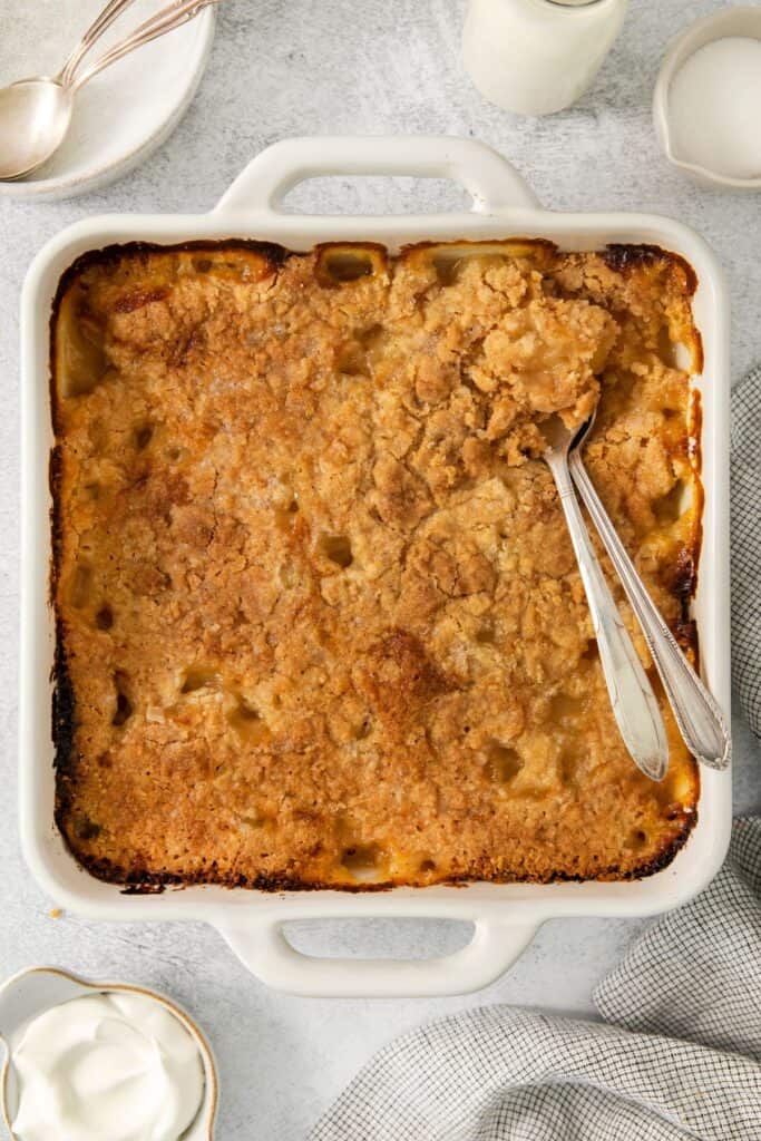 Baked peach cobbler with a spoon in the baking dish.
