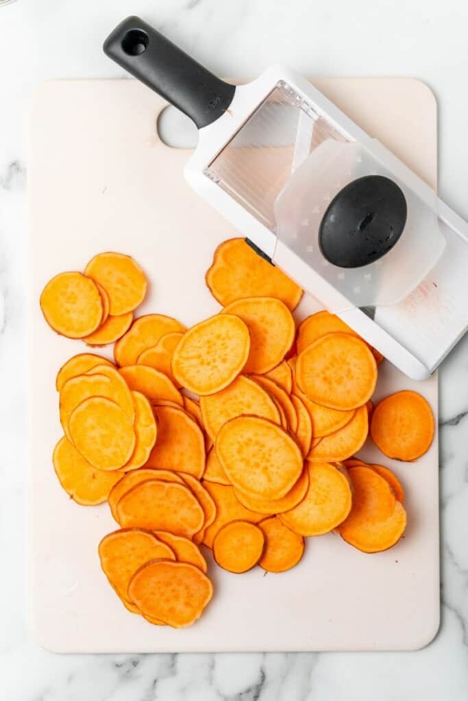 A mandolin being used to slice sweet potatoes.