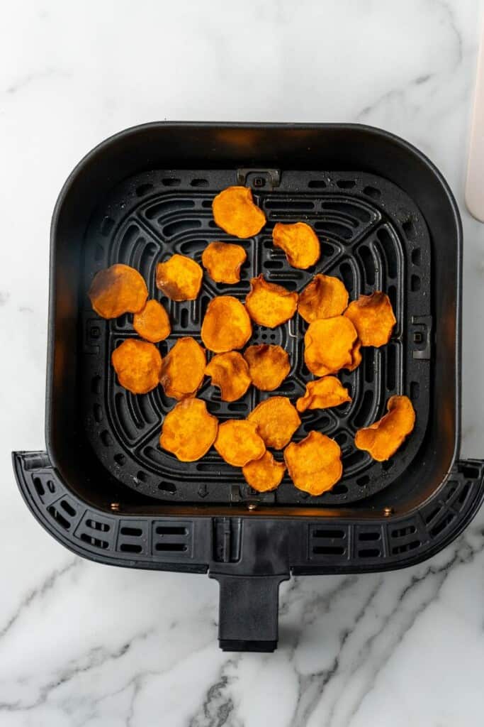 Air Fried Sweet Potato slices resting in a black air fryer basket.