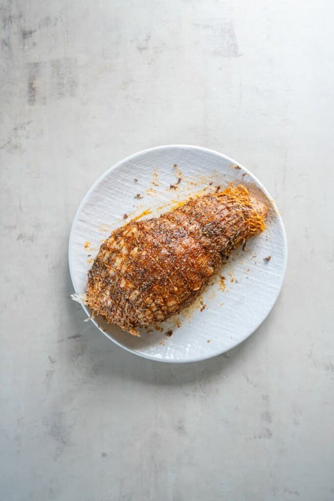 Herbs and seasonings rubbed onto an uncooked turkey breast.