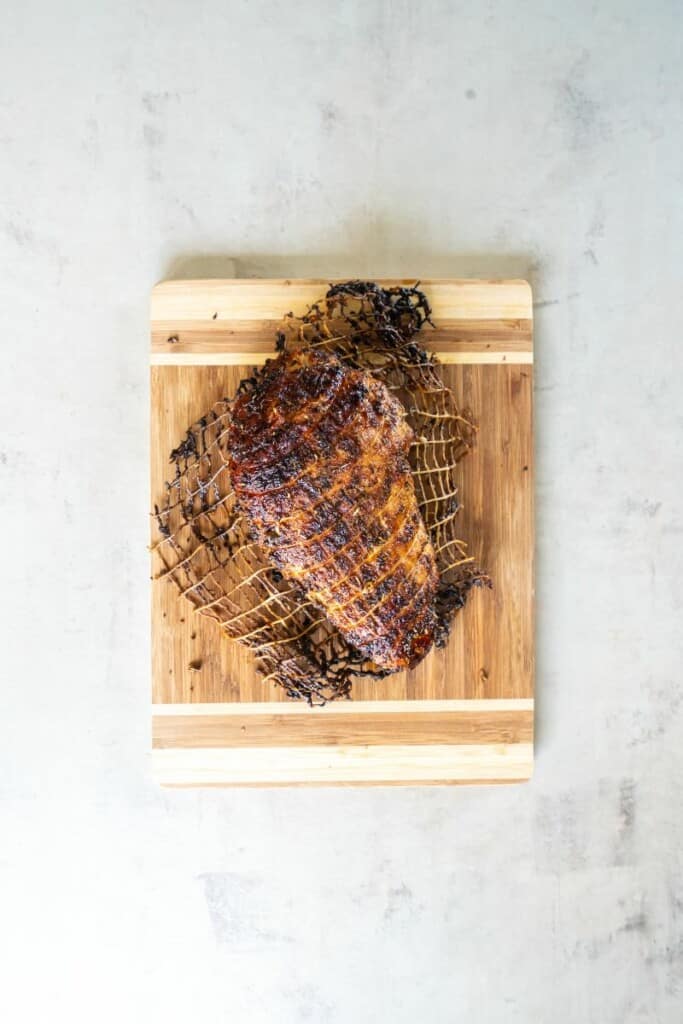 Fully cooked seasoned turkey breast resting on a wooden cutting board.