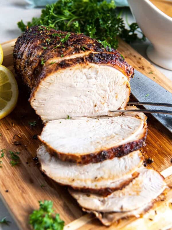 Turkey breast sliced and resting on a wooden cutting board.