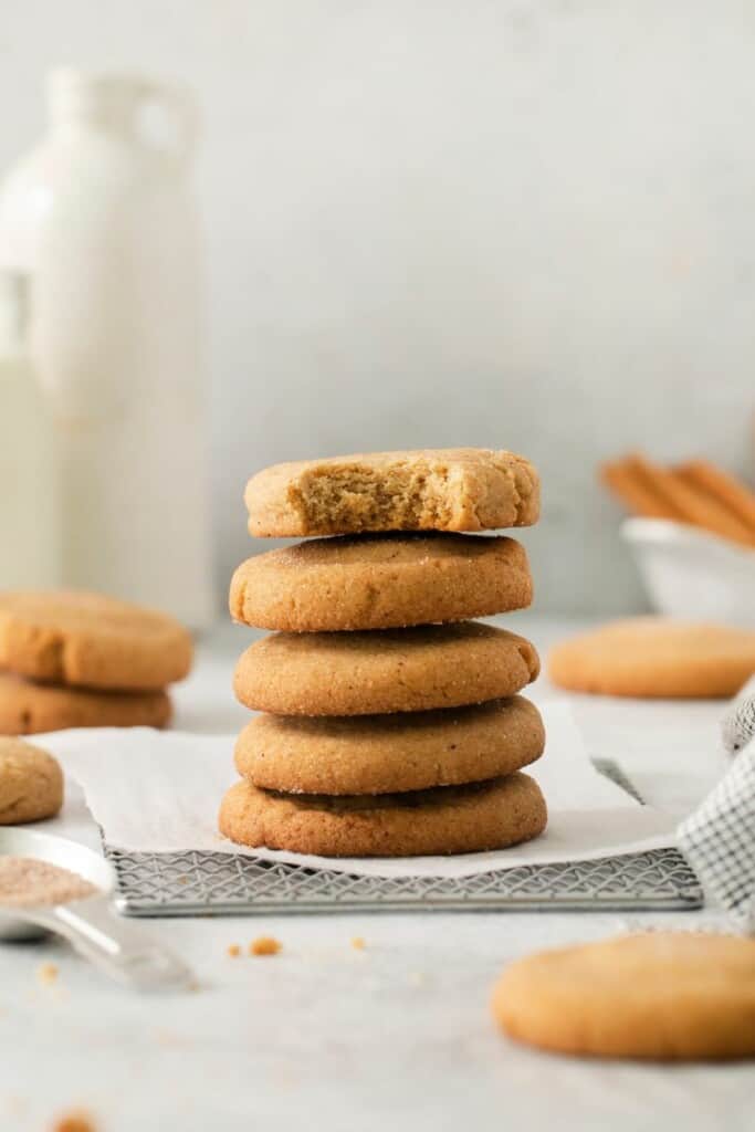 A stack of snickerdoodle cookies, the top cookie has one bite removed.