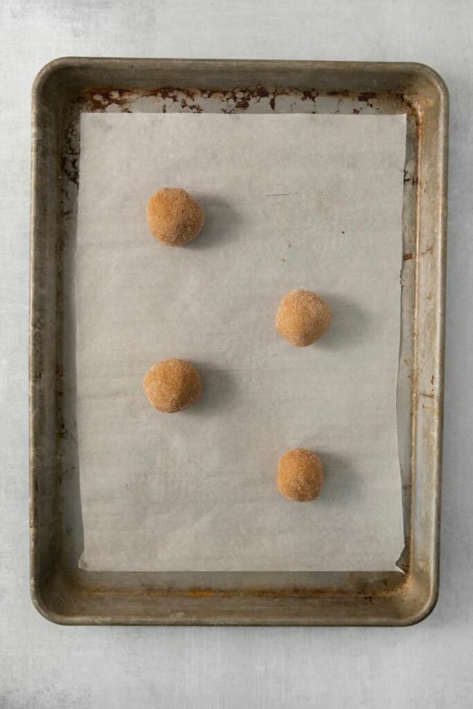 Sugared dough balls on a parchment lined cookie sheet.