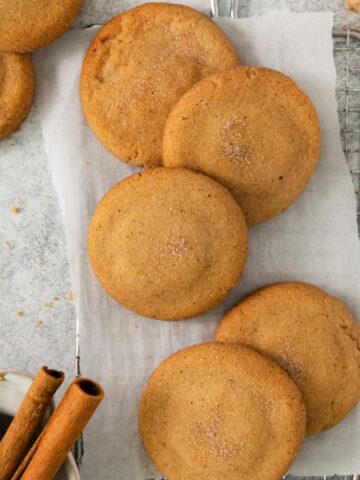 Snickerdoodles with Brown Butter on parchment paper with cinnamon sticks