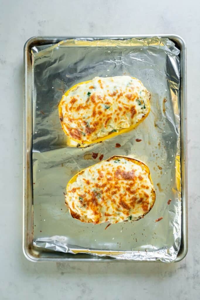 Roasted spaghetti squash with chicken alfredo on a foiled lined baking sheet.