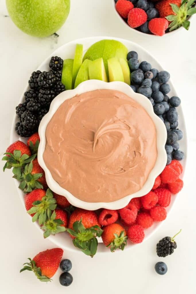 Chocolate fruit dip in a white bowl surrounded by fresh fruit.