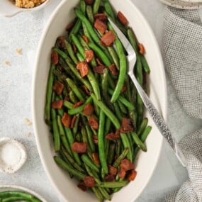 Green beans with bacon in an oblong serving dish with a fork.