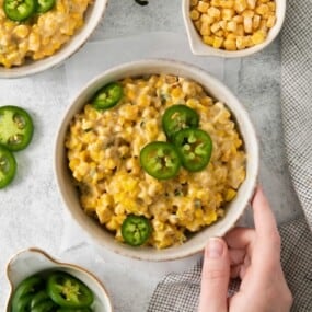 A bowl of jalapeno cream corn surrounded by extra ingredients.