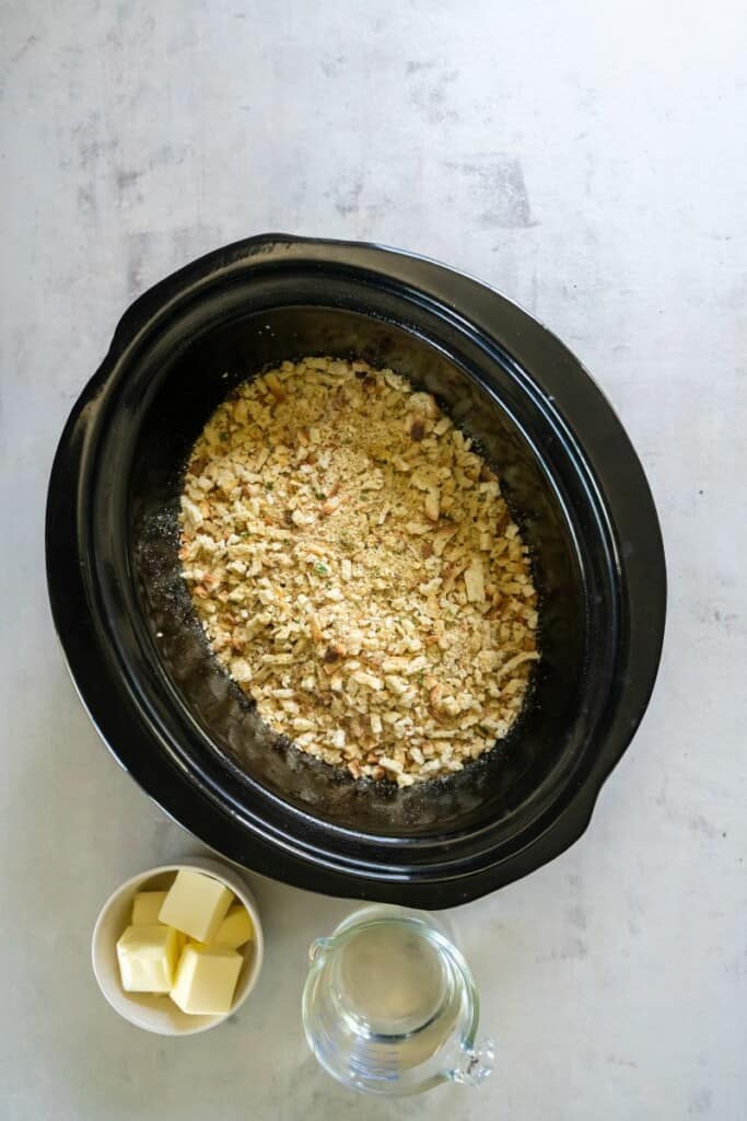 Stuffing poured over the top of chicken breasts in a crock pot.