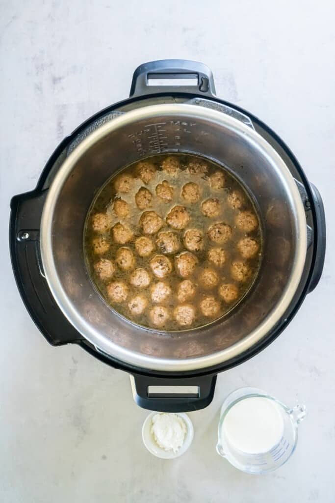 Frozen meatballs in an Instant Pot with beef broth and seasonings.