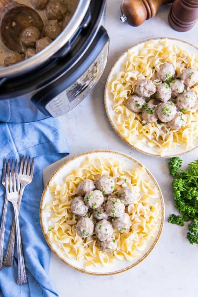 Two bowls filled with prepared meatballs and pasta.