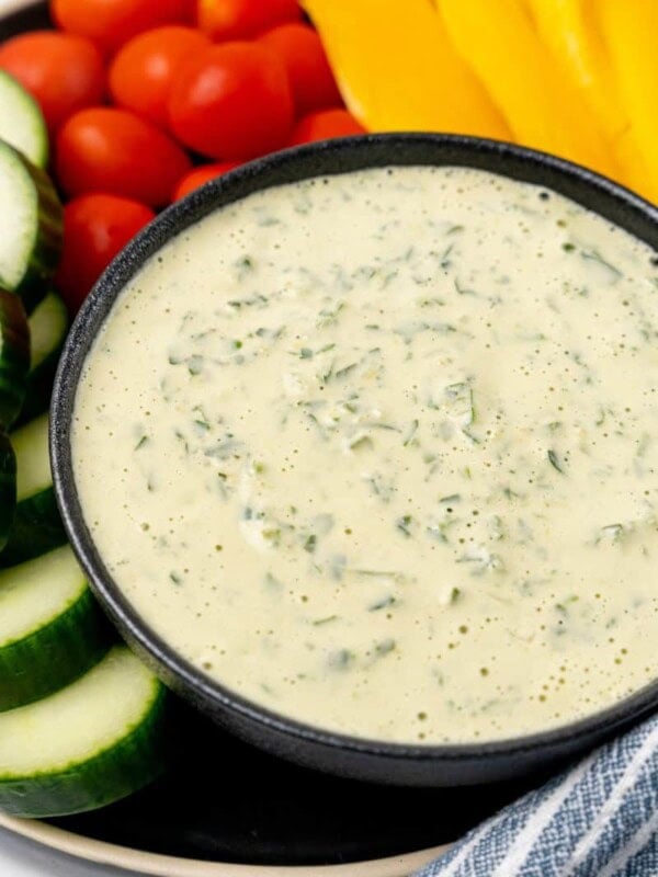 A bowl of lemon herb tahini surrounded by fresh vegetables.