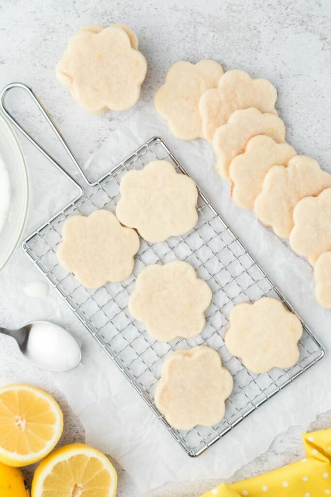 A batch of glazed lemon shortbread cookies on a cooling rack.