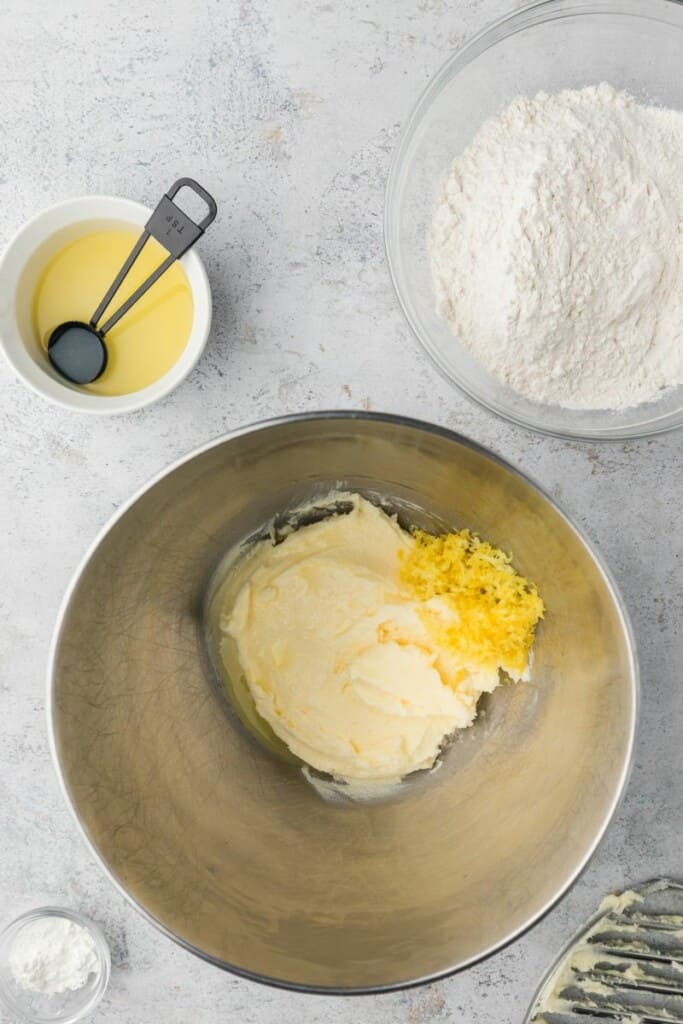 Adding lemon juice and lemon zest to butter and sugar mixture in a mixing bowl.