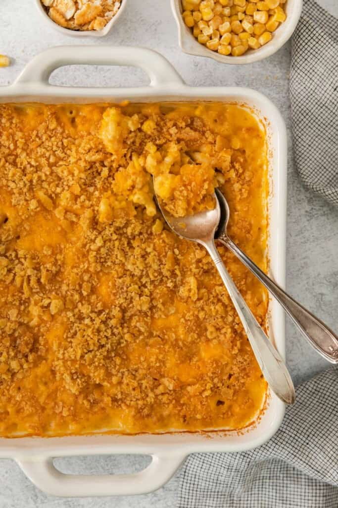 Two spoons resting on top of a corn macaroni casserole.