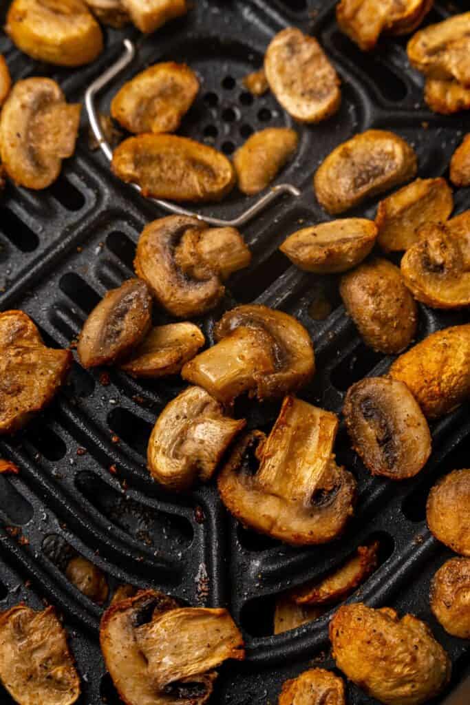 Close up of air fried mushrooms inside the air fryer basket still.