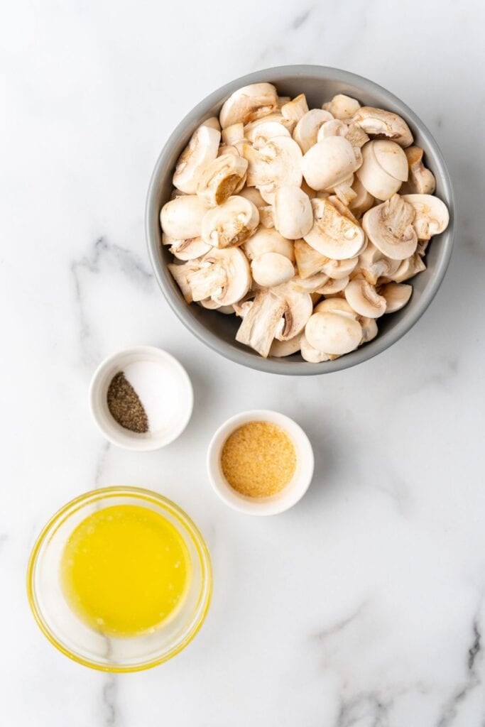 Ingredients needed to make air fryer mushrooms: white button mushrooms, butter, garlic powder, salt, pepper, and parsley.