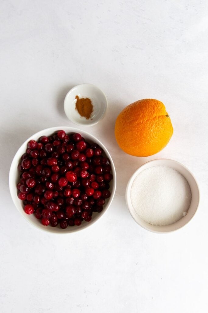 Ingredients needed to make cranberry orange sauce: cranberries, orange zest, orange juice, sugar, and cinnamon,