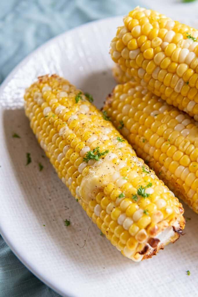 four pieces of corn on the cob on a plate with butter on top
