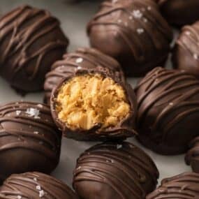 Chocolate peanut butter balls with rice krispies with one with a bite taken out so you can see the inside.