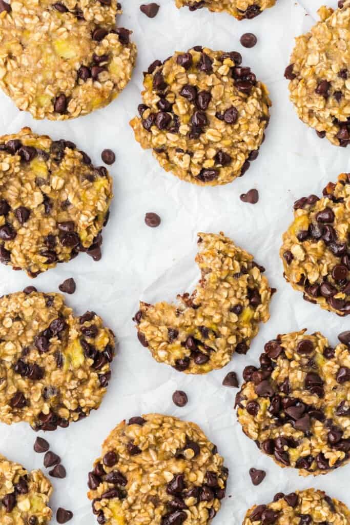 Several chocolate chip oatmeal cookies laying flat, the center cookie has a bite removed.