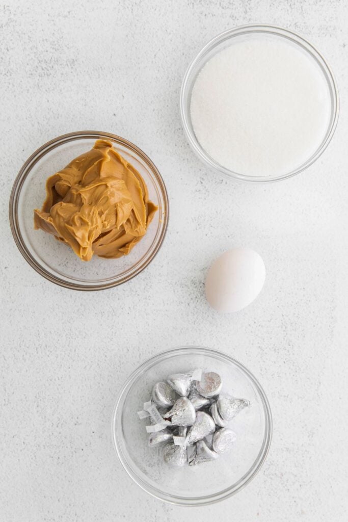 Ingredients needed to make 3-ingredient peanut butter blossoms: sugar, creamy peanut butter, egg, and Hershey kisses.