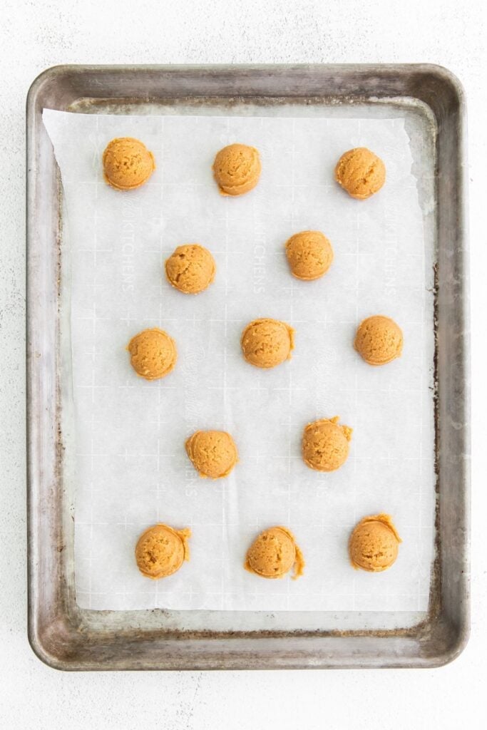 Easy peanut butter cookies dough balls on a cookie sheet with parchment paper ready to be baked.