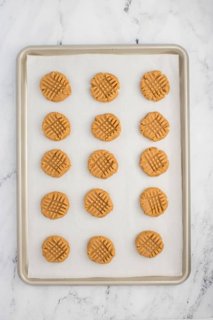 Baked peanut butter cookies on a parchment lined baking sheet.