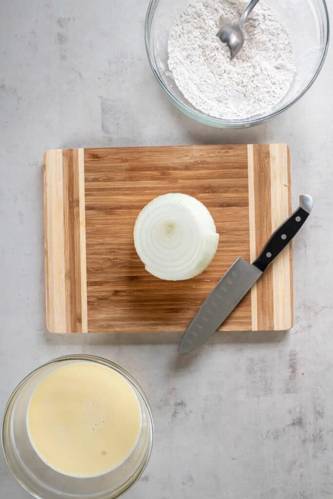 Preparing an onion for a blooming onion by slicing off the ends.