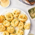 Garlic Knots on a white plate with melted butter in the background.