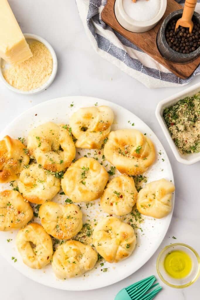 Garlic Knots on a white plate with melted butter in the background.
