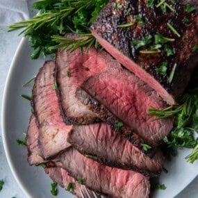 Overhead view of air fryer roast beef half sliced on a serving plate.